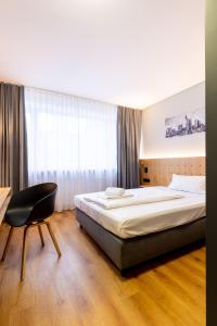 - une chambre avec un lit, un bureau et une chaise dans l'établissement mk hotel frankfurt, à Francfort-sur-le-Main