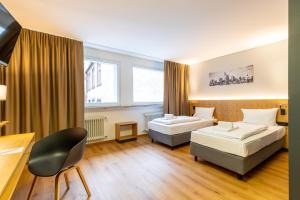 ein Hotelzimmer mit 2 Betten und einem Stuhl in der Unterkunft mk hotel frankfurt in Frankfurt am Main