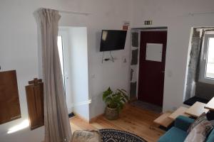 a living room with a couch and a tv on a wall at Casas da Ribeira in Santa Bárbara