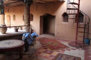 una habitación con una persona sentada en una silla en un edificio en Dar Amazir en Agdz