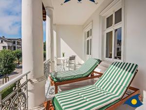 two green chairs on a balcony with a table at Villa Linde Whg 06 in Heringsdorf +12 photos