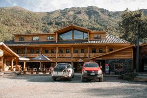 two cars parked in front of a large wooden building at Las Bravas Lodge in Las Trancas
