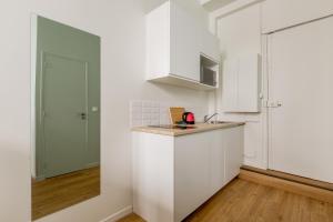 cocina con armarios blancos y encimera en Appartement Panthéon - Feuillantines, en París