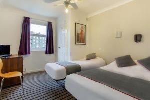 a hotel room with two beds and a desk at Enrico Hotel in London