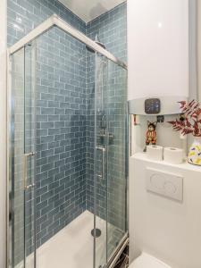 y baño con ducha de azulejos azules. en Appartement Panthéon - Feuillantines, en París