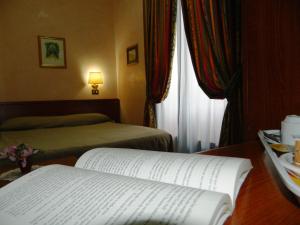 a room with two beds and a book on a table at Buonarroti Home in Rome