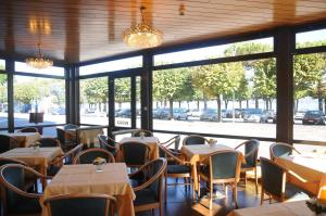 um restaurante com mesas, cadeiras e janelas em Hotel Italie et Suisse em Stresa