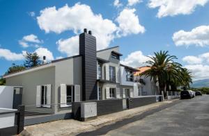 una casa bianca con una palma di fronte di Beach House DeLuxe a Glória