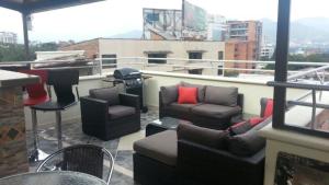 uma varanda com sofás e cadeiras num telhado em Calle 8 Suites em Medellín