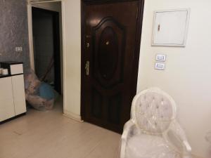 カイロにあるManial CAIRO شقه فرش مودرن 145متر علي شارع المنيل الرئيسي جزيرة المنيل الروضة قريبه جدا من النيلの木製のドアと白い椅子が備わる客室です。