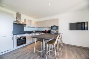 eine Küche mit weißen Schränken und einem Tisch mit Stühlen in der Unterkunft Résidence Pierre & Vacances Premium Les Terrasses d'Arsella in Porto-Vecchio