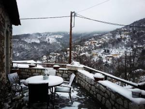 a table and chairs on a balcony covered in snow at Tholos in Áno Dholianá
