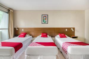 two beds in a room with red and white sheets at OYO Rio Colinas Hotel, Rio de Janeiro in Rio de Janeiro