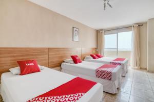 um quarto com 3 camas com almofadas vermelhas e brancas em OYO Rio Colinas Hotel, Rio de Janeiro no Rio de Janeiro