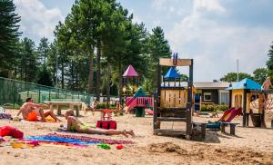 a group of people laying in the sand at a playground at Verblijfpark Tulderheyde - Leisure only! in Poppel