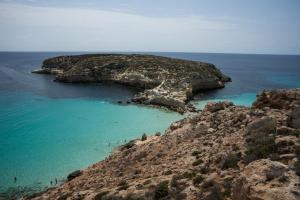 un gruppo di persone che nuotano nell'acqua vicino a un'isola rocciosa di I Dammusi di Borgo Cala Creta a Lampedusa
