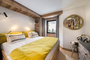 a bedroom with a large bed with a yellow blanket at Appartement Flocon - LES CHALETS COVAREL in Val dʼIsère