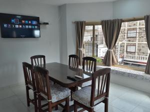 Una mesa de comedor con cuatro sillas y un televisor. en Departamentos37Depto1, en Santa Teresita