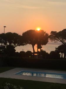 una puesta de sol sobre una piscina con árboles y el océano en gardasee sirmione, en Sirmione
