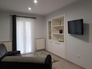- un salon avec un canapé et une télévision murale dans l'établissement Ca la Quima, à La Seu d'Urgell
