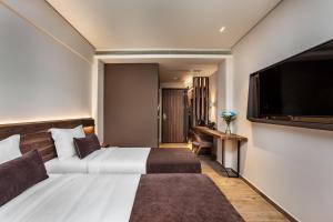um quarto de hotel com uma cama e uma televisão de ecrã plano em Imperial Plus Urban Smart Hotel Thessaloniki em Tessalônica