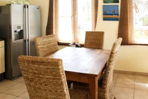 a dining room table with chairs and a refrigerator at Kunuku Villa in Oranjestad