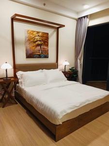 a bedroom with a large bed with two tables and a painting at Eyu@Timurbay Seaview Residence in Kuantan