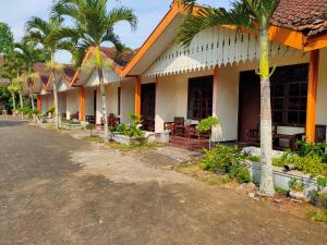 a row of houses with palm trees next to a street at OYO 2465 Hotel Raung View in Banyuwangi