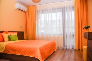 - une chambre avec un lit orange et une grande fenêtre dans l'établissement Sunny, à Bourgas