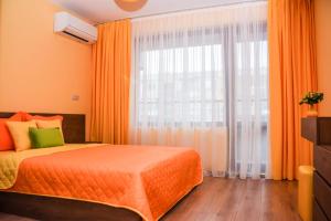 a bedroom with an orange bed and a large window at Sunny in Burgas