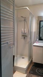 La salle de bains est pourvue d'une douche avec une porte en verre. dans l'établissement STUDIO MEUBLE Face mer vue imprenable sur la mer, parking et fibre gratuits, à Les Sables-dʼOlonne