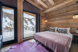 um quarto com uma cama e uma grande janela em Penthouse Chamois - LES CHALETS COVAREL em La Daille