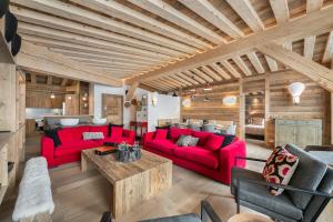 una sala de estar con muebles rojos y techos de madera. en Penthouse Chamois - LES CHALETS COVAREL en La Daille