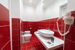 uma casa de banho com azulejos vermelhos, um lavatório e um WC. em HG Boutique Toledo, Napoli Centro, by ClaPa Group em Nápoles