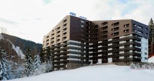 a large building with snow in front of it at Apartament 902 Alpin Resort Poiana Brasov in Poiana Brasov