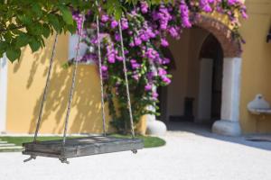 a swing with purple flowers hanging from a building at Agriturismo La Filanda in Manerba del Garda