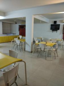 a cafeteria with yellow tables and chairs and a flat screen tv at Sai Maa Resort And Convention Centre in Puttaparthi