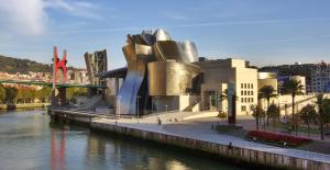 a building next to a river next to a bridge at Pensión Bilbao in Bilbao