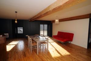 ein Wohnzimmer mit einem Tisch und einem roten Sofa in der Unterkunft Gite de la Ferme de Maria Blanca in Bielle
