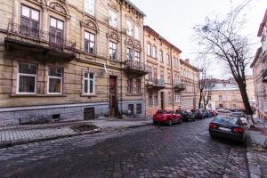 a cobblestone street with cars parked in front of buildings at Квартира в центрі вулиця Балабана 29 біля Краківського ринку in Lviv