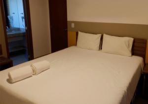 - un grand lit blanc avec une serviette dans l'établissement Apartamento em Resort de Olimpia, à Olímpia 8 autres photos