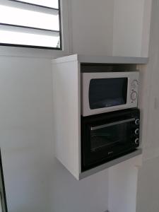 a microwave sitting on a shelf in a wall at Résidence B&L Lagon : Bungalow Corail in Sainte-Luce