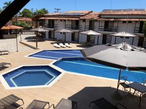 a swimming pool with umbrellas and chairs and a building at Rede Andrade Estrela Dalva Praia Hotel in Porto Seguro