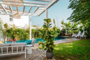 eine Terrasse mit einer weißen Pergola und einem Pool in der Unterkunft Island Home Seaside Villa in Paralimni