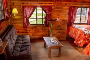 a living room with a couch and a bed in a log cabin at Villa Mexicana Creel Mountain Lodge in Creel