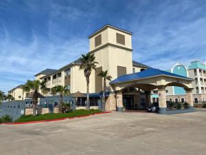 um grande edifício com palmeiras em frente em Galveston Beach Hotel em Galveston