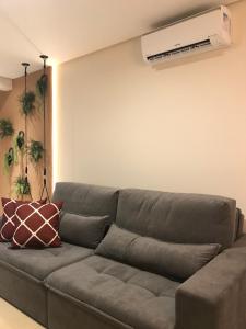 een woonkamer met een bank en airconditioning aan de muur bij Apartamento Vêneto in Canela