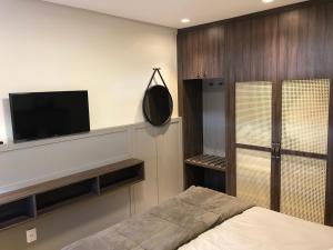 a bedroom with a bed and a flat screen tv at Apartamento Vêneto in Canela