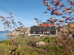 a house on top of a hill next to the ocean at Ilimanaq Lodge in Ilmanaq
