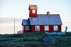 a red house on top of a hill at Ilimanaq Lodge in Ilmanaq